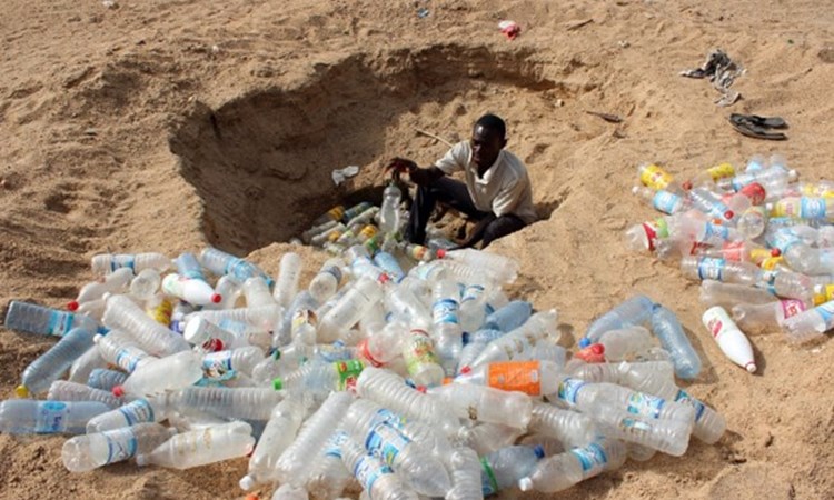 Man digging a hole to bury plastic waste