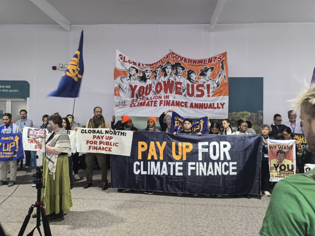 picture of protesters with banners saying: 'you owe us!'